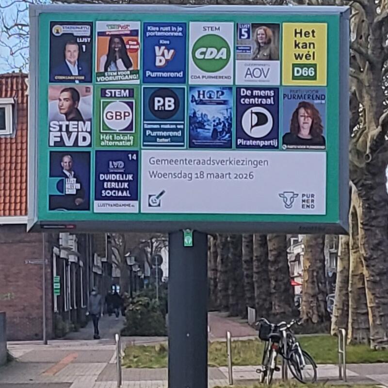 Gemeentelijk reclamebord met de affiches van alle 14 deelnemende partijen aan de gemeenteraadsverkiezingen 2026